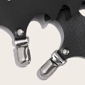 Détail de jarretière aile de chauve-souris gothique, gros plan cuir PU noir et clip en métal.