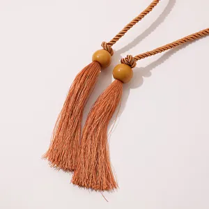 Detailed close-up of bohemian tassel belt fringe, woven rope and decorative beads element.