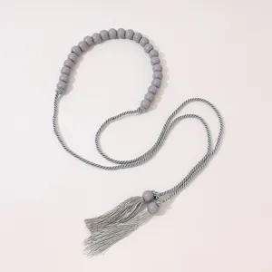 Grey wooden bead tassel rope detail, elegant decorative waist accessory or craft element.