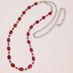 Close-up detail of silver waist chain with red oval rhinestones, elegant fashion accessory.