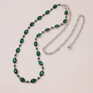 Close-up detail of silver-tone metal waist chain featuring sparkling green crystal stones.