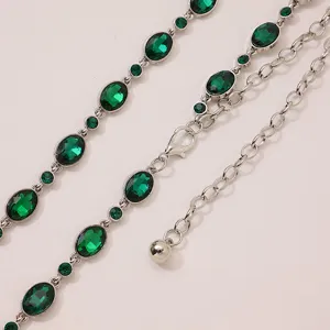 Close-up detail of silver-toned metal waist chain adorned with sparkling green rhinestones.