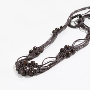 Primo piano dettagliato di una cintura in corda di cera intrecciata con perle di legno.