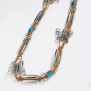 Bohemian braided waist belt detail showing silver tubes, blue beads, and butterfly charms.