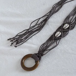 Close-up detail of bohemian brown macrame waist belt featuring natural shell and wood ring.
