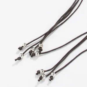 Boho braided waist rope detail with silver metal beads and handmade knots close up.