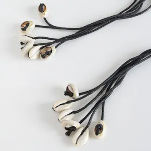 Close-up detail of bohemian handmade waist rope with natural cowrie shells and black woven cords.