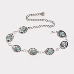 Detailed view of western style metal chain belt with turquoise stones and carved buckle.
