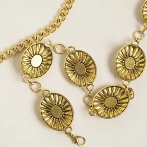 Close-up detail of metallic gold waist chain featuring radiant oval coin links and chunky links.