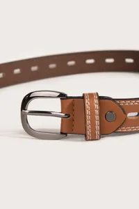 Detailed close-up of brown leather women belt featuring contrast stitching and gunmetal buckle.