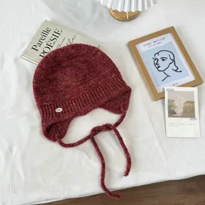 Detailansicht der warmen geflochtenen Ohrenklappen Mütze in gemischter roter Farbe.
