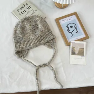 Gemütliche, mehrfarbig gesprenkelte Strickmütze mit Ohrenklappen und geflochtenen Bändern.