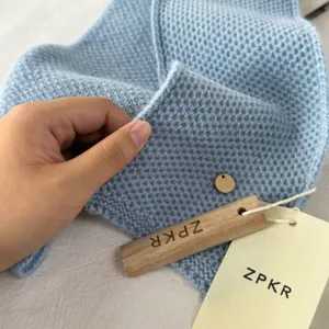 Nahaufnahme des weichen hellblauen Strickschals mit feiner Textur und Markenschildern.