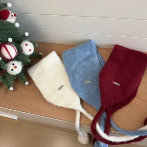Detailed view of cute knitted earflap hats with pom-poms and ties in three colors.