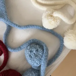 Detailed view of cute Korean style knitted earmuffs with soft pom poms for winter warm.