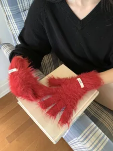 Detailed shot of vibrant red fuzzy split-finger touchscreen gloves with cute decorative tags.