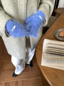 Detailed view of fluffy blue touch screen gloves worn in cozy winter outfit setup.