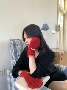 Close-up showcase of cozy red fluffy winter gloves worn by model, soft plush touch details.