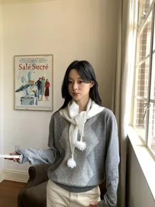Dettaglio della sciarpa in maglia bianca morbida con nappe di perle pompon carine.