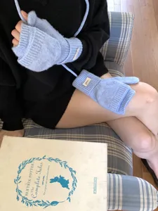 Detail view of light blue knitted convertible fingerless gloves with string and cute label.