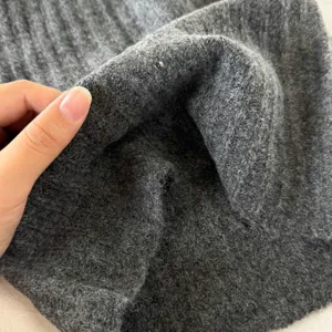 Detail de tissu en tricot gris fonce, texture chaude de tour de cou gros plan.