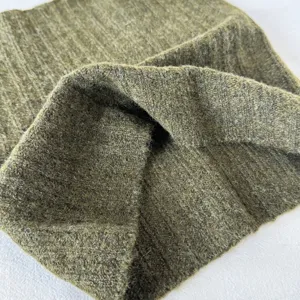 Gros plan détaillé du tour de cou en tricot côtelé vert olive doux montrant texture et chaleur.