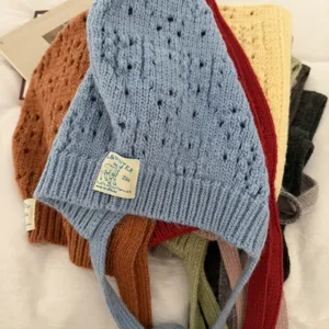 Detailed view of colorful hollow knit balaclava hats with earflaps and ties, cozy style.
