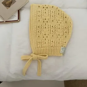 Close-up detail of the yellow hollow knit balaclava bonnet hat, showing delicate texture.