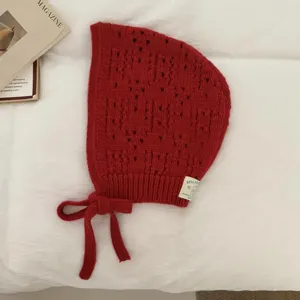 Red knitted balaclava hat with hollow design and cute ties, comfortable warm winter hood.