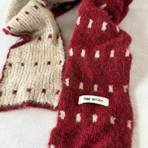 Cozy color-block knitted scarf detail showing soft textured fabric and chic woven label design.
