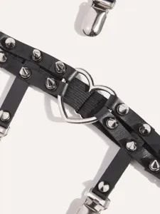 Detailed close-up of gothic punk black PU leather garter belt with metal spikes and heart ring.