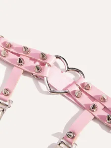 Pink punk style leg garter close-up, featuring metal spikes and heart ring hardware.