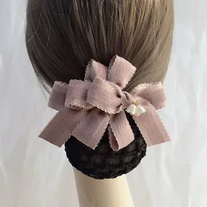 Detailed close-up of professional hair net bun cover with elegant pink bow and cute charm.