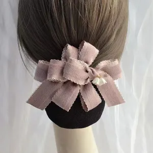Detailed view of the elegant pink fabric bow hair net with a delicate pearl pendant.
