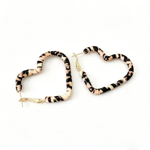 Elegantes pendientes de aro en forma de corazón tejido con estampado animal y detalles dorados.