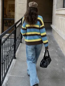 Vue détaillée en extérieur montrant le pull en tricot à rayures colorées de dos avec jean.