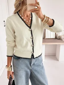 Chic V-neck knit cardigan with contrast black trim and metallic buttons for elegant styling.