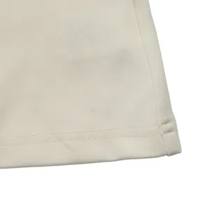 Detailed view of the elegant beige dress hem, showing exquisite stitching craftsmanship.