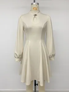 Close-up detail of the retro mock neck, elegant keyhole cutout and metal clasp on beige dress.