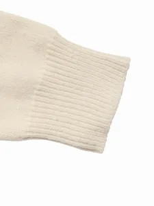Close up detail view of the soft knitted winter sweater ribbed cuffing texture in off white.