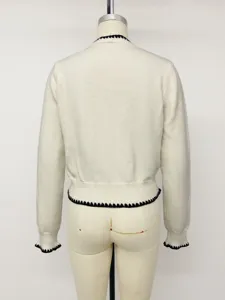Classic white knit cardigan with elegant black scalloped trim, long sleeves and button front.