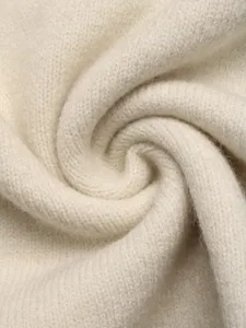Close-up detail of soft beige knit fabric texture, fine wool yarn weave for autumn winter.