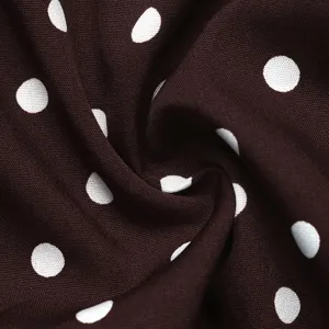 Close-up detail of dark brown fabric with classic white polka dot pattern for women's apparel.