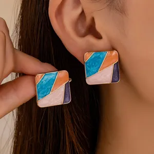 Vue de détail de boucles d'oreilles carrées géométriques aux motifs multicolores.