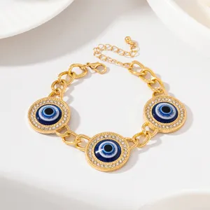 Bracelet breloque mauvais œil doré avec strass scintillants, design à triple cercle élégant.