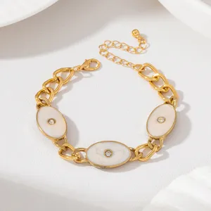 Bracelet chaîne épaisse doré avec breloques ovales en émail blanc et strass brillants.