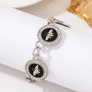 Bracelet vintage abeille strass avec charme rond émail noir et chaîne maillons argent.