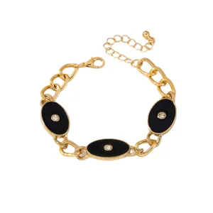 Bracelet à chaîne grosse ton or avec breloques ovales émaillées noires et incrustations de strass.
