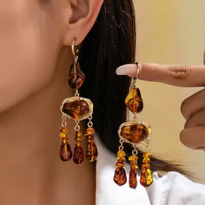 Vue détaillée des boucles d'oreilles en résine ambrée, design de pampilles de style bohème.