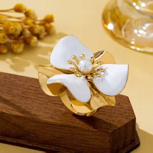 Vue détaillée d'une bague florale statement avec pétales émaillés blancs et perle.